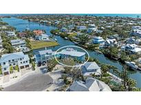 Waterfront home with a metal roof surrounded by mature landscaping and a private dock along the canal at 511 Loquat Dr, Anna Maria, FL 34216
