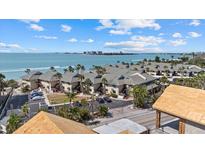 Stunning aerial view of a beachfront property with multiple buildings, palm trees, and oceanfront access at 6924 Bochi Cir, Sarasota, FL 34242