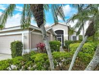 Beautiful home exterior with lush landscaping, including palm trees and colorful plants at 9411 Forest Hills Cir, Sarasota, FL 34238