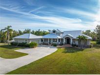 Stunning home features a metal roof, inviting front porch, and a spacious driveway on a well-manicured lawn at 1355 Debrecen Rd, Sarasota, FL 34240