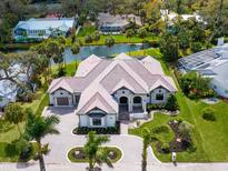 Stunning aerial view of a luxurious home with a tile roof, lush landscaping, and waterfront access at 1575 Eastbrook Dr, Sarasota, FL 34231