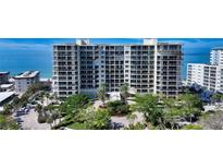 A beautiful condominium complex is shown with well manicured landscaping and beachfront access on a bright sunny day at 1800 Benjamin Franklin Dr # B208, Sarasota, FL 34236