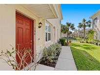 Charming red front door entrance to this inviting home, beautifully landscaped with lush greenery at 8323 Enclave Way # 104, Sarasota, FL 34243