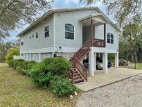 Elevated two-story home featuring a spacious covered parking area and charming front yard landscaping at 1160 Mill Creek Rd, Bradenton, FL 34212