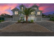 Stunning two-story coastal home with a lush palm tree and a paver driveway, capturing serene beachside living at 215 83Rd St, Holmes Beach, FL 34217