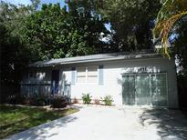 Charming single-story home with a concrete driveway, light grey exterior, blue shutters and landscaping at 4031 Iola Dr, Sarasota, FL 34231