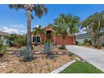 Charming single-story home with a beautiful, lush tropical landscaped front yard and a matching terracotta-colored exterior at 5227 Lansdowne Way, Palmetto, FL 34221