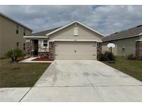 Beige single story home with a 2 car garage, stone accents and well maintained front yard at 5838 Elegant Orchid Way, Sarasota, FL 34232