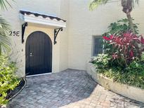 Charming courtyard entrance with arched door, brick pavers, and lush landscaping at 6101 34Th W St # 25E, Bradenton, FL 34210