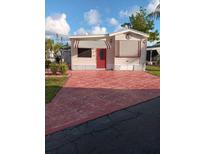 Charming single-story home featuring an inviting red door and striped awnings at 1674 University Pkwy # 389, Sarasota, FL 34243