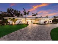 Inviting single-story home features a lush lawn, palm trees, and a paver driveway leading to a bright entry at 1806 Caribbean Dr, Sarasota, FL 34231