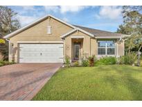 Charming single-story home featuring a manicured lawn, brick driveway, and attached two-car garage at 2756 Canoe Ln, North Port, FL 34286