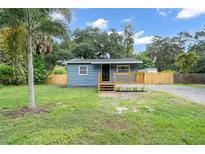 Charming cottage-style home featuring blue siding, a wood deck, and a spacious front yard at 3561 Elfers Pkwy, New Port Richey, FL 34655