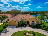 Stunning lakefront home boasts lush landscaping, circular driveway, and tile roof, offering a luxurious and inviting curb appeal at 4520 Longspur Ln, Sarasota, FL 34238