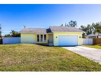 Charming single-story home with a well-maintained lawn and two-car garage, freshly painted in a sunny yellow hue at 4659 Alligator Dr, Venice, FL 34293