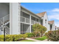 Condominium exterior featuring screened lanais, mature landscaping, and convenient stairwell access at 6707 Stone River Rd # 105, Bradenton, FL 34203