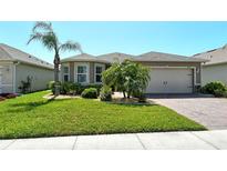 Charming single-story home featuring well-manicured landscaping and a brick driveway leading to a two-car garage at 8996 Excelsior Loop, Venice, FL 34293