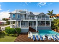 Resort-style backyard oasis features a sparkling pool, outdoor bar, spiral staircase, and lush landscaping at 110 10Th S St, Bradenton Beach, FL 34217
