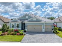 Charming home featuring a three-car garage, paver driveway, well-manicured lawn, and colorful flower beds at 13306 Deep Blue Pl, Bradenton, FL 34211