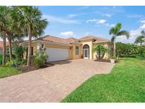Charming home featuring a barrel tile roof, brick driveway, and tropical landscaping at 13320 Coluccio St, Venice, FL 34293