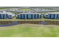 Aerial view of a light blue condo complex surrounded by lush green grass and a serene lake at 14061 Heritage Landing Blvd # 412, Punta Gorda, FL 33955