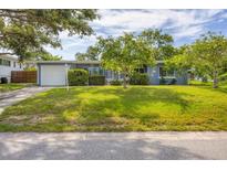 Charming single-story home with a well-manicured lawn and mature trees, creating a welcoming curb appeal at 2566 Tulip St, Sarasota, FL 34239