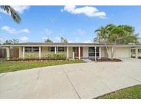 Charming single-story home with a well-manicured lawn, palm trees, and a concrete driveway at 2905 Bougainvillea St, Sarasota, FL 34239