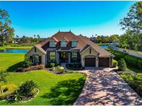 A beautiful waterfront home with a manicured lawn, lovely landscaping, and a brick driveway under a clear blue sky at 3712 59Th Avenue E Cir, Ellenton, FL 34222