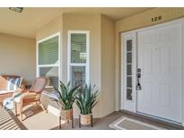 Inviting condo front door with decorative plants and chair seating on the porch at 5211 Mahogany Run Ave # 126, Sarasota, FL 34241