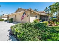 Charming single-story home featuring a well-manicured lawn, attached garage, and an American flag at 7183 Wood Creek Dr # 9, Sarasota, FL 34231