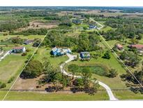Expansive aerial view of a rural property with a pond, lush greenery, and a charming light blue home with metal roof at 7677 Saddle Creek Trl, Sarasota, FL 34241