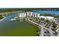 An aerial view showcases the building and its waterfront location with palm trees and parking at 10530 Boardwalk Loop # 201, Lakewood Ranch, FL 34202