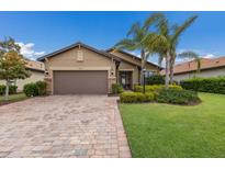Charming single-story home with lush landscaping, brick driveway, and a two-car garage at 16719 Ellsworth Ave, Bradenton, FL 34202