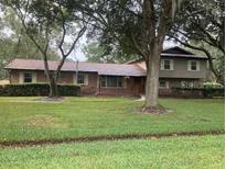 Charming two-story home with lush landscaping and mature trees on an expansive green lawn at 411 El Greco Dr, Brandon, FL 33511