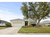 Charming single-story home featuring a well-manicured lawn, mature tree, and attached two-car garage at 4691 Claremont Park Dr, Bradenton, FL 34211