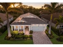 Beautiful single Gathering home with mature landscaping, brick driveway, and a two-car garage at 5557 Long Shore Loop, Sarasota, FL 34238