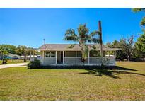Charming single-story home featuring a cozy front porch, mature trees, and a well-maintained lawn at 5860 Brown Ln, Sarasota, FL 34232