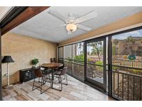 Relaxing screened patio with stylish wood-look tile floors, ceiling fan, and outdoor dining set at 6342 Midnight Pass Rd # 212, Sarasota, FL 34242