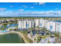 Stunning aerial view of a lakeside condominium complex featuring lush landscaping and ample parking at 10520 Boardwalk Loop # 503, Bradenton, FL 34202