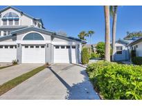 Charming coastal-style home with a well-manicured lawn, multi car garage, and a neatly paved driveway on a sunny day at 1239 Siesta Bayside Dr # 1239C, Sarasota, FL 34242