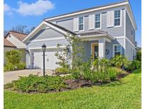 Charming two-story home showcasing a manicured lawn, inviting curb appeal, and a two-car garage at 12959 Seasong Ter, Bradenton, FL 34211