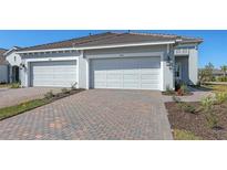 Charming home exterior featuring a brick driveway leading to a two-car garage with a well-manicured lawn at 18137 Franklin Park Ct, Venice, FL 34293