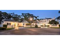 Stately home with lush landscaping, circular drive, and elegant architectural details at twilight at 236 Saint James Park, Osprey, FL 34229