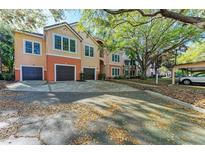 Two-story condo featuring attached garages, colorful stucco, and lush trees at 4110 Central Sarasota Pkwy # 123, Sarasota, FL 34238