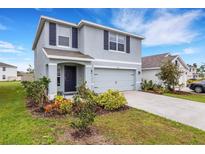Two-story home featuring gray paint, a two-car garage, and colorful landscaping at 4231 Autumn Fog Ct, Palmetto, FL 34221