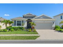 Charming single-story home with a well-manicured lawn, stone accents, and a two-car garage on a sunny day at 5744 Woodland Sage Dr, Sarasota, FL 34238