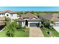 Beautiful home with a well-manicured lawn, brick driveway, and tropical landscaping, located on a golf course at 5817 Brandon Run, Bradenton, FL 34211
