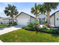 Charming home with a well-manicured lawn, lush landscaping, and inviting curb appeal with palm trees and clean driveway at 5998 Amberly Dr, Bradenton, FL 34208