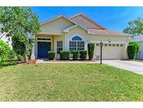 Charming home featuring a well-manicured lawn, a blue door with wreaths, and mature landscaping at 6415 Fetterbush Ln, Lakewood Ranch, FL 34202