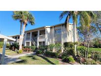 Inviting condominium exterior boasts lush landscaping and a well-maintained two-story building with palm trees at 7151 Wood Creek Dr # 205, Sarasota, FL 34231